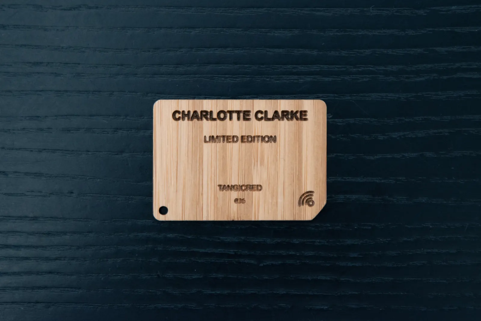A laser-engraved bamboo card on dark wood: Charlotte Clarke, Limited Edition, TangiCred, number 29